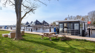 Houseboat Aqua Dolce presso Welcome In - Friesland, Paesi Bassi, vista su prato, tavolo e sull’acqua.
