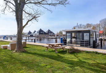 Houseboat Aqua Dolce presso Welcome In - Friesland, Paesi Bassi, vista su prato, tavolo e sull’acqua.