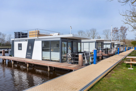 Hausboot Aqua Dolce bei Welcome In - Friesland, Niederlande, mit Holzsteg und moderner Architektur.
