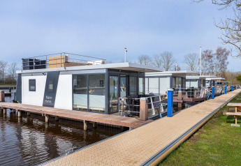 Modern houseboat Aqua Dolce at Welcome In - Friesland, Netherlands, features wooden dock and water view.
