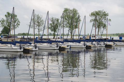 Veleros atracados en Houseboat Aqua Dolce en Welcome In - Friesland, Países Bajos, reflejados en el agua.