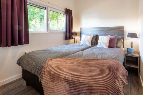 Gezellige slaapkamer in Module Wellness lodge, Recreatiepark het Esmeer, tweepersoonsbed en sfeervolle inrichting.