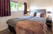 Schlafzimmer der Module Wellness Lodge im Recreatiepark het Esmeer mit gemütlichem Doppelbett und stilvollen Details.