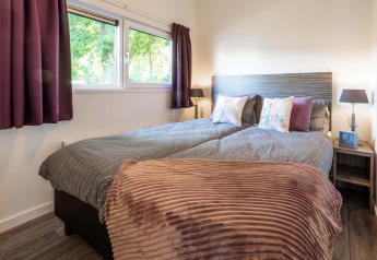 Schlafzimmer der Module Wellness Lodge im Recreatiepark het Esmeer mit gemütlichem Doppelbett und stilvollen Details.