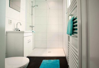 Salle de bain moderne au Module Wellness (Spa) du Recreatiepark het Esmeer avec carrelage blanc et accents turquoise.