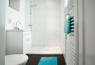 Baño moderno en Module Wellness (Spa) en Recreatiepark het Esmeer con azulejos blancos y detalles en turquesa.