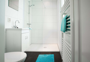 Baño moderno en Module Wellness (Spa) en Recreatiepark het Esmeer con azulejos blancos y detalles en turquesa.