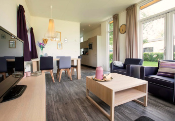 Salon moderne dans la lodge Module Wellness (Spa) au Recreatiepark het Esmeer, grandes fenêtres et déco cosy.