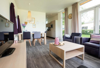 Moderne leefruimte in de lodge Module Wellness (Spa) op Recreatiepark het Esmeer, met grote ramen en gezellige stijl.