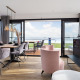 Modernes Hausboot-Wohnzimmer mit Seeblick, Esstisch und bequemen Stühlen in hellem Design.