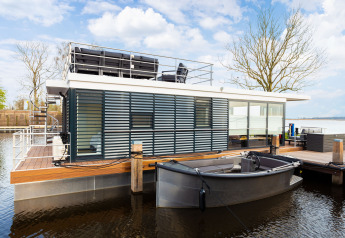 Casa flotante moderna 'de Valreep' con terraza y bote en Welcome In - Friesland, Países Bajos.