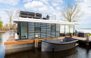 Péniche moderne 'de Valreep' avec terrasse sur le toit et bateau à Welcome In - Friesland, Pays-Bas.