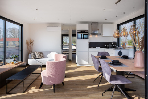 Modernes Wohnzimmer und Küche auf Hausboot 'de Valreep' mit großen Fenstern in Friesland, Niederlande.