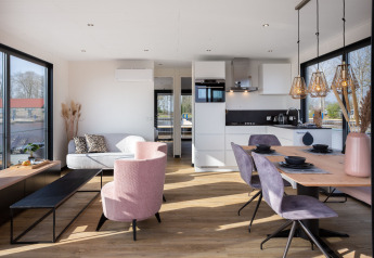 Moderne woonkamer en keuken op woonboot 'de Valreep' met grote ramen in Friesland, Nederland.