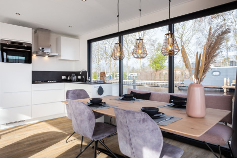 Comedor y cocina modernos en la casa flotante 'de Valreep' en Friesland, Países Bajos, con grandes ventanales.