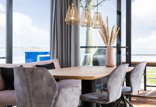 Modern dining area on a houseboat with large windows, lake view, and stylish decor in Friesland, Netherlands.