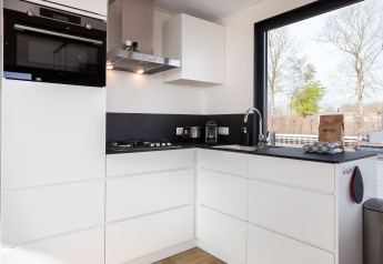 Cuisine moderne sur le houseboat 'de Valreep' avec grandes fenêtres et placards blancs à Friesland, Pays-Bas.