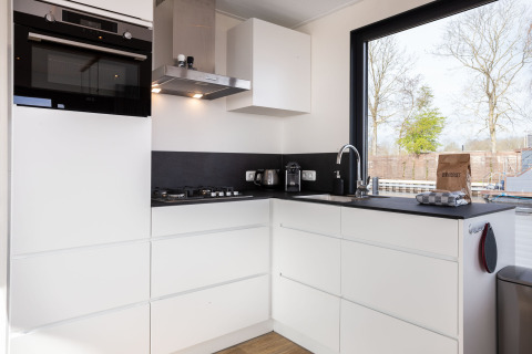 Cuisine moderne sur le houseboat 'de Valreep' avec grandes fenêtres et placards blancs à Friesland, Pays-Bas.