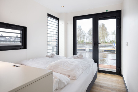 Dormitorio moderno en el barco casa 'de Valreep' en Welcome In - Friesland, Países Bajos, con vista al agua.