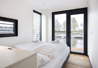Dormitorio moderno en el barco casa 'de Valreep' en Welcome In - Friesland, Países Bajos, con vista al agua.