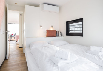 Luminoso dormitorio en la casa flotante 'de Valreep' con cama doble, toallas limpias y ventana lateral.
