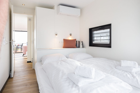 Lyst og moderne soveværelse på husbåd 'de Valreep' med dobbeltseng, vindue og rent sengetøj.