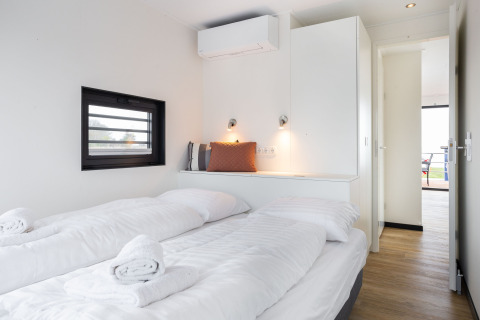 Modernes Schlafzimmer auf Hausboot 'de Valreep' mit weißen Betten, Fenster und minimalistischer Einrichtung.