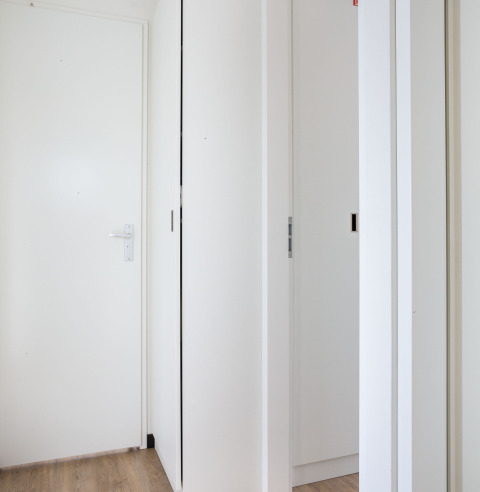 Pasillo interior de la casa flotante 'de Valreep' con puertas blancas y suelo de madera clara en Friesland, NL.