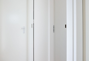 Couloir intérieur de la péniche 'de Valreep' avec portes blanches et plancher clair à Friesland, Pays-Bas.