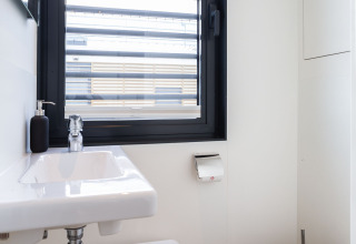 Baño moderno en la casa flotante 'de Valreep' en Welcome In - Friesland, Países Bajos, con ventana y lavabo.