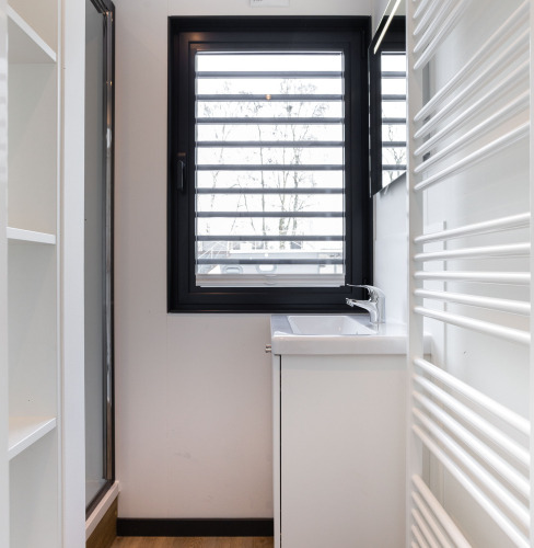 Baño moderno en la casa flotante 'de Valreep' con ventana, lavabo y radiador en Friesland, Países Bajos.