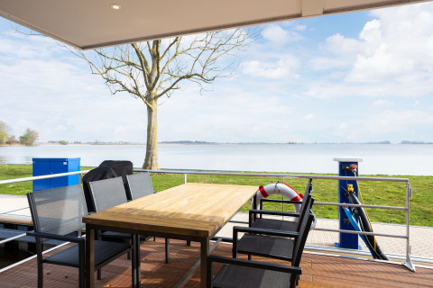 Udsigt fra terrasse på husbåden 'de Valreep' ved Welcome In - Friesland, med sø og landskab i baggrunden.