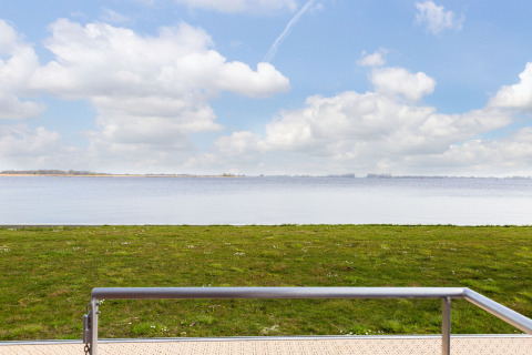 View from houseboat 'de Valreep' at Welcome In - Friesland with green grass and lake in the Netherlands.