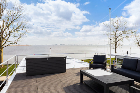 Terrasse eines Hausboots mit modernen Möbeln und Seeblick bei Welcome In - Friesland, Niederlande.