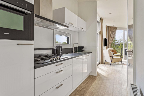 Cuisine moderne et salon à la Natuurlodge Wellness du Recreatiepark het Esmeer, Pays-Bas, avec vue extérieure.