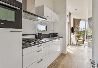 Cucina moderna e salotto alla Natuurlodge Wellness presso Recreatiepark het Esmeer, Paesi Bassi, con vista.