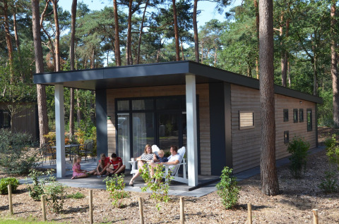 Family relaxing on the porch of Forest Park Chalet at Holiday park De Kleine Belties, Netherlands.