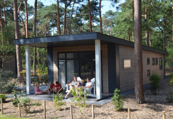 Familie nyder det udendørs på terrassen ved Forest Park Chalet i Holiday park De Kleine Belties i Holland.