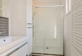Baño moderno con ducha de cristal y lavabo en Forest park chalet, Holiday park De Kleine Belties, Países Bajos.