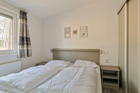 Heldere slaapkamer in Forest park chalet bij Holiday park De Kleine Belties, Nederland, met twee eenpersoonsbedden.
