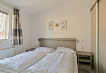 Heldere slaapkamer in Forest park chalet bij Holiday park De Kleine Belties, Nederland, met twee eenpersoonsbedden.