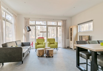 Moderne stue i Forest park chalet, Holiday park De Kleine Belties, med store vinduer og naturligt lys.