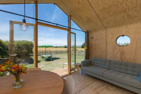 Innenaufnahme eines Wikkelhouse in Zeeland, Niederlande, mit moderner Einrichtung und Blick ins Grüne.