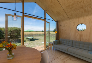 Interieur van een Wikkelhouse in Zeeland, Nederland, met modern design en zicht op de groene tuin.