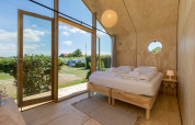 Interior de una acogedora Wikkelhouse en Welcome In - Zeeland con cama doble y puertas de cristal al jardín.