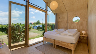 Interior de una acogedora Wikkelhouse en Welcome In - Zeeland con cama doble y puertas de cristal al jardín.