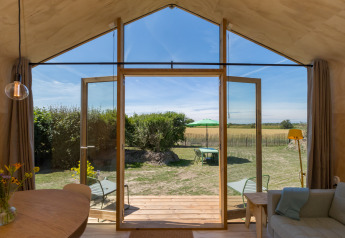 Binnenaanzicht vanuit een Wikkelhouse in Zeeland, Nederland, met open deuren naar tuin en velden.