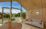 Interieur van een Wikkelhouse met lichte sofa en uitzicht op de natuur bij Welcome In - Zeeland, Nederland.