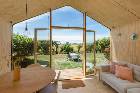 Interior de una Wikkelhouse en Welcome In - Zeeland, con vistas al jardín y al campo en los Países Bajos.