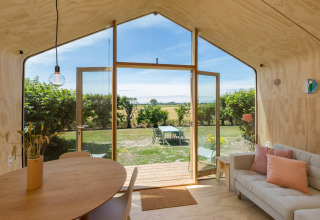 Interior de una Wikkelhouse en Welcome In - Zeeland, con vistas al jardín y al campo en los Países Bajos.